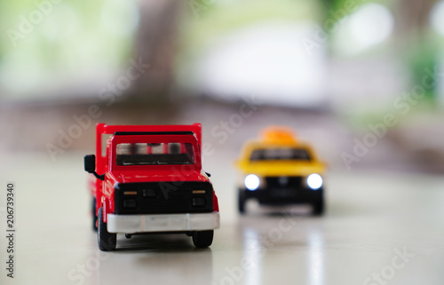 Red toy car truck and yellow old taxi car on road on blurred background, traffic and drive concept