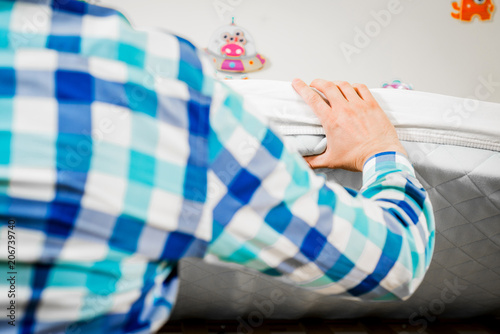 Construction of bed for children. Man arranges a mattress on a cot for a child. Role of the father in child's life. Father folds bed for a newborn child, growing up children, Concept of parenthood.