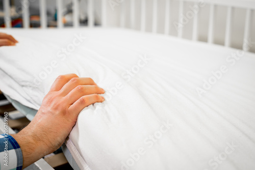 Construction of bed for children. Man arranges a mattress on a cot for a child. Role of the father in child's life. Father folds bed for a newborn child, growing up children, Concept of parenthood. photo