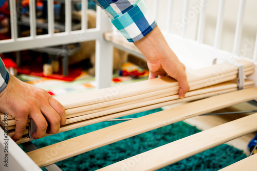 Construction of bed for children. The man puts the bed frame. Role of the father in child's life. Father folds bed for a newborn child, growing up children, Concept of parenthood.