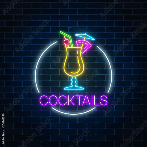 Neon cocktail glass sign in circle frame on dark brick wall background. Glowing gas advertising with alcohol shake.