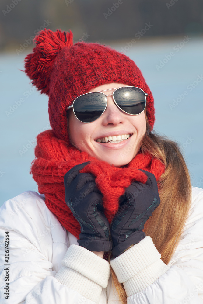 redhead skinny girl in aviator sunglasses, red cap, red scarf and white  winter jacket smiling substituting face to sunlight Stock Photo | Adobe  Stock