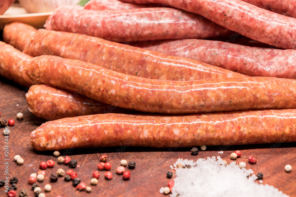 raw sausages with chilli and herbs on a wooden board with spices raw sausages with chilli and herbs on a wooden board with spices
