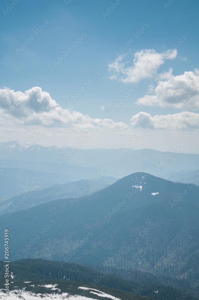 A beautiful view of the snow-capped mountains of the Carpathians from the top of Goverly in spring in a beautiful sunny day with light clouds. Carpathians, Goverla, Ukraine.