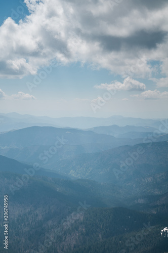A beautiful view of the snow-capped mountains of the Carpathians from the top of Goverly in spring in a beautiful sunny day with light clouds. Carpathians, Goverla, Ukraine. © bubligg