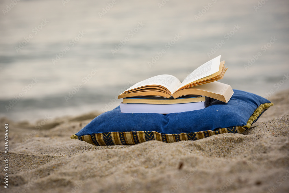 Open book on a beach by the sea. Summer reading book Open book on a beach by the sea. Summer reading book