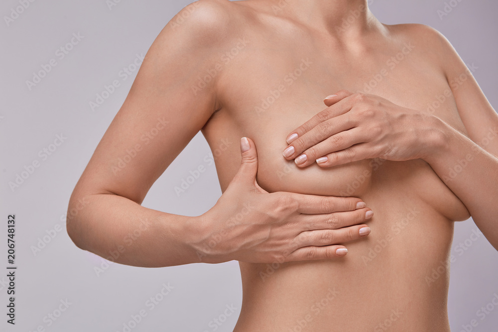 Young topless woman doing breast self-exam (BSE). Checking up breast changes, possible lumps, distortions or swelling. Breast cancer awareness. Young topless woman doing breast self-exam (BSE). Checking up breast changes, possible lumps, distortions or swelling. Breast cancer awareness.