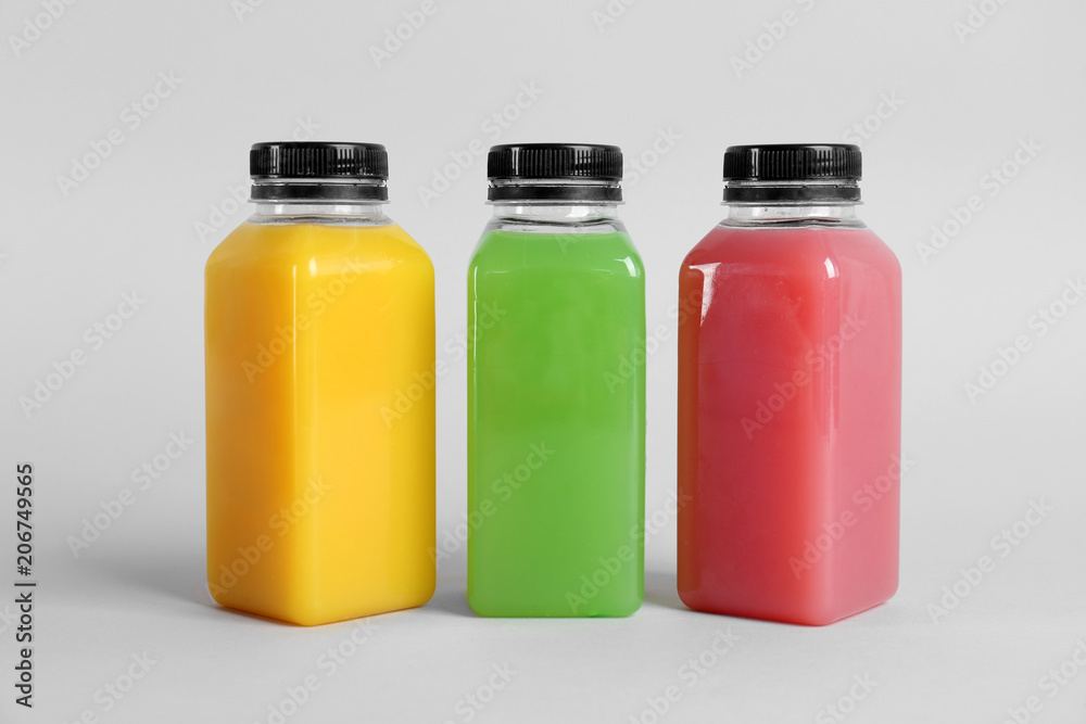 Bottles with delicious colorful juices on light background Bottles with delicious colorful juices on light background
