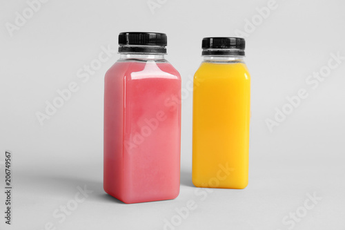 Bottles with delicious colorful juices on light background
