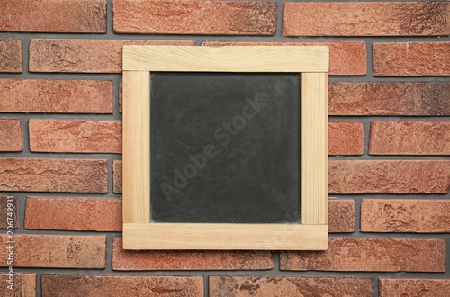 Small clean chalkboard hanging on brick wall