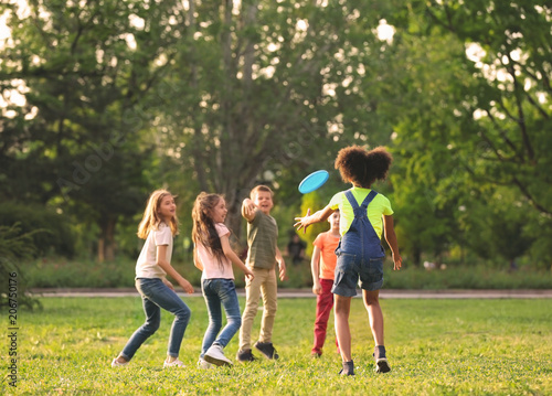 Cute little children playing with frisbee outdoors on sunny day photo