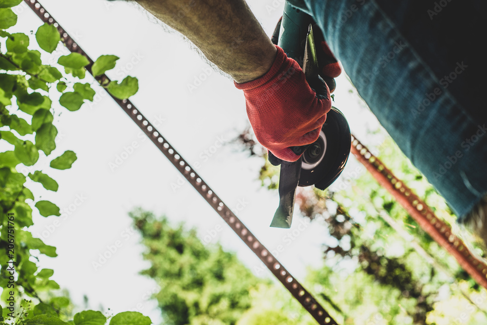 The man is sharp with the mower's knife with a grinder, sparks fly from