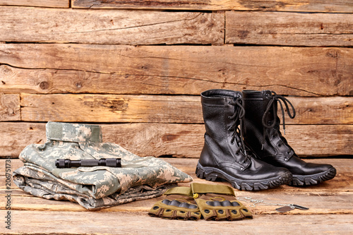 Set of military clothes and equipment. Wooden desk surface background.