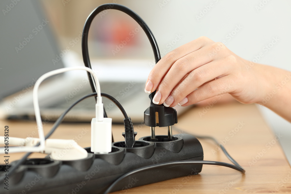 Woman hand plugging a plug in an electrical socket Woman hand plugging a plug in an electrical socket