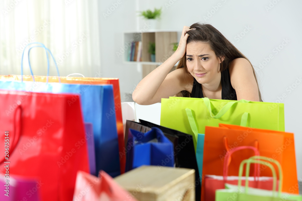 Worried shopaholic woman after multiple purchases - obrazy, fototapety, plakaty 