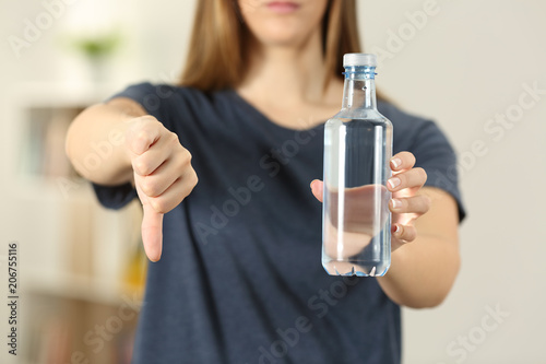Woman hands holding a bottle of water with thumbs down
