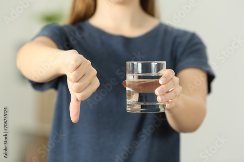 Woman holding a water glass with thumbs down