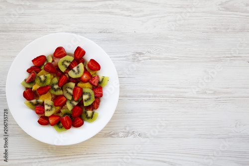 Fresh fruit salad on white wooden background, top view. Copy space.