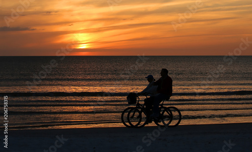 Couple ride side by side enjoying the sunset and getting their exercise on beautiful Fort Myers Beach, Florida, USA