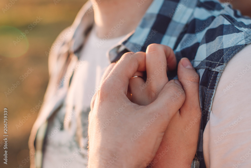 The girl hugs her young man and the guy's hand holds her hand tightly against his chest. Side view close-up with space for your text