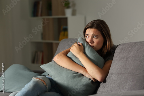 Fotografering Scared teen at home embracing pillow
