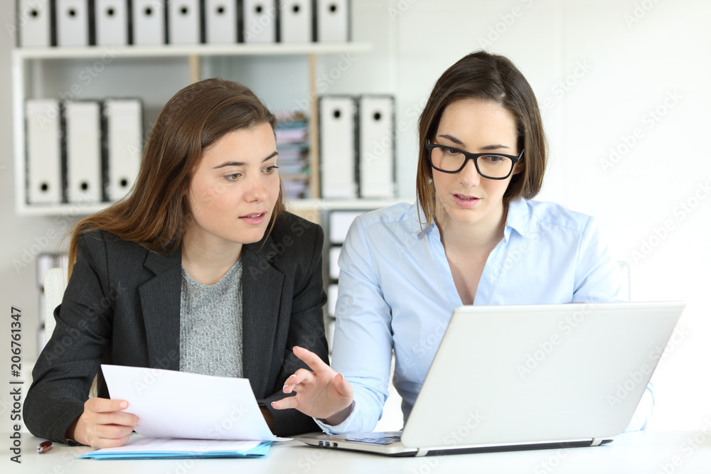Office workers comparing documents on-line Office workers comparing documents on-line