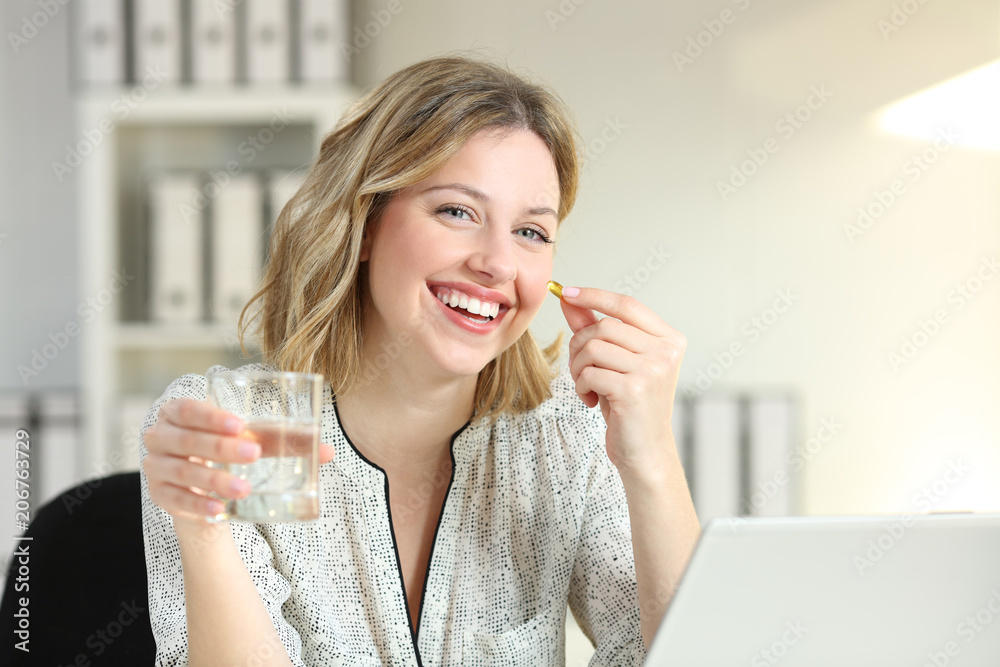 Happy office worker showing a vitamin supplement pill Happy office worker showing a vitamin supplement pill