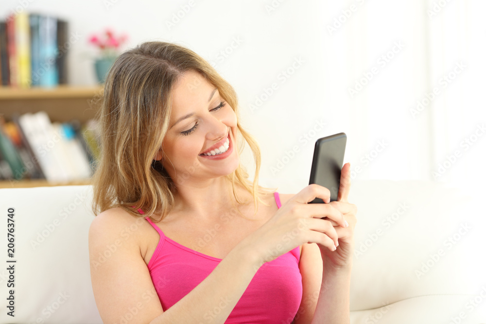 Smiley girl using a smart phone sitting on a couch Smiley girl using a smart phone sitting on a couch