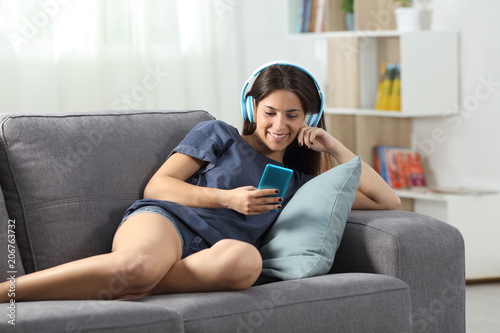 Happy teen listening to music with phone and headphones