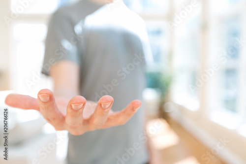Man holding his hand out and showing something in a bright room
