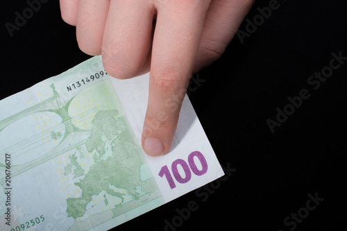 Hand holding 100 euro banknote on a black background photo