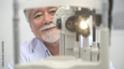 Optician at work in hospital. Senior chinese optician using eye scanner, POV style. Eye care concept. Zoomin focus shot.