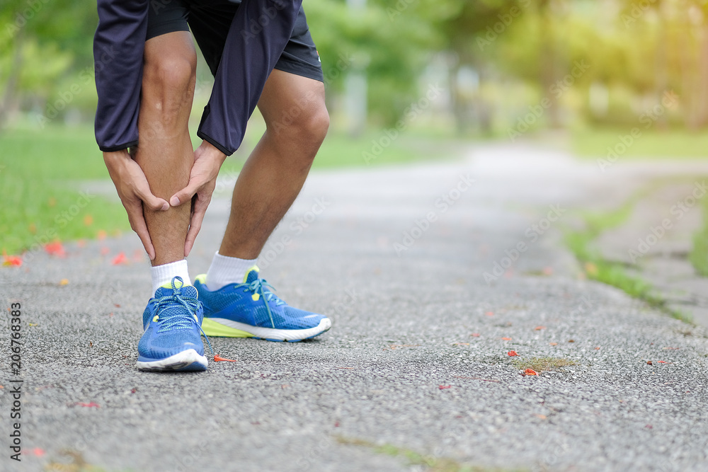 Young fitness man holding his sports leg injury, muscle painful during