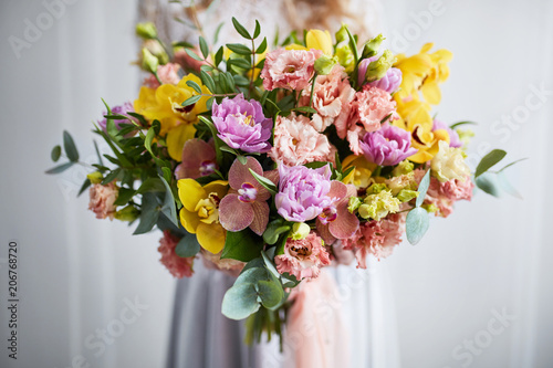 Spring bouquet of flowers with orchids, tulips and eustoma. Pink yellow flower arrangement