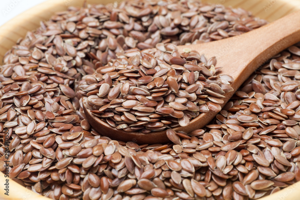 Flax seeds with spoon in a wooden bowl. Close-up. Flax seeds with spoon in a wooden bowl. Close-up.