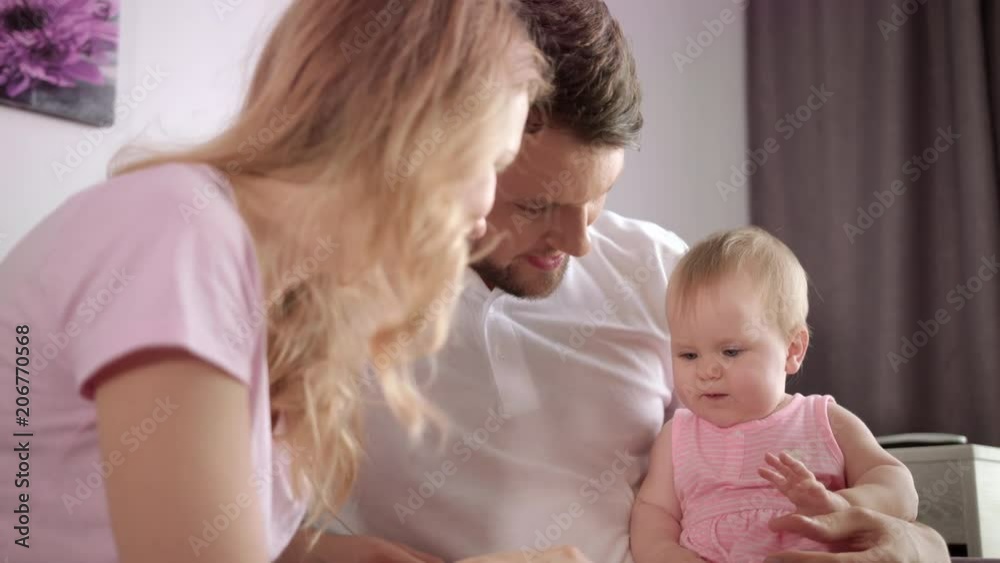 Family leisure time. Sweet baby girl sitting on father hands and playing with mom. Happy family concept. Woman and man with child at home. Parent and child playing togetherness Family leisure time. Sweet baby girl sitting on father hands and playing with mom. Happy family concept. Woman and man with child at home. Parent and child playing togetherness