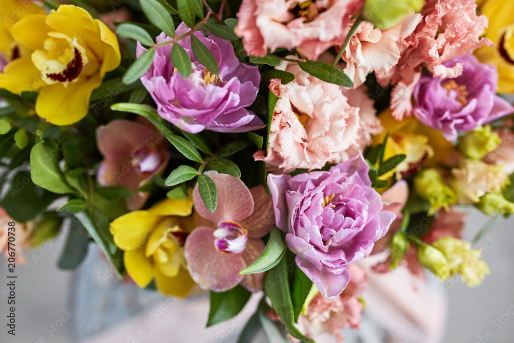 Spring bouquet of flowers with orchids, tulips and eustoma. Pink yellow flower arrangement