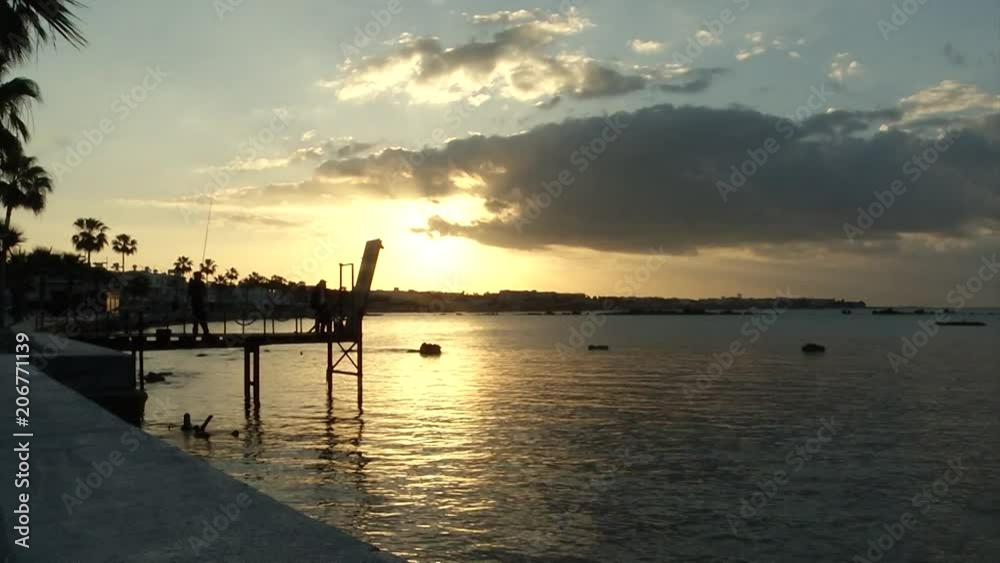 Time lapse of a silhouetted dock over water with a golden sunset Time lapse of a silhouetted dock over water with a golden sunset