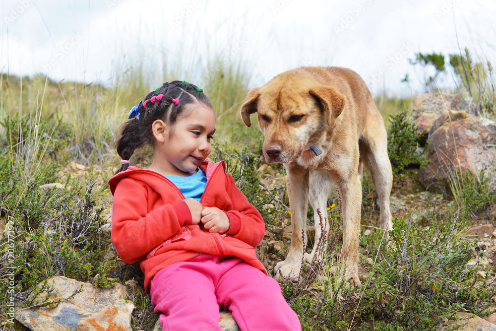 Little latin girl with her big dog in the countryside.