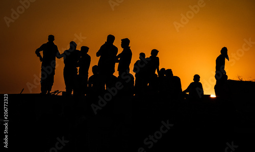 Silhouette of people standing on roof watching festivities below at sunset