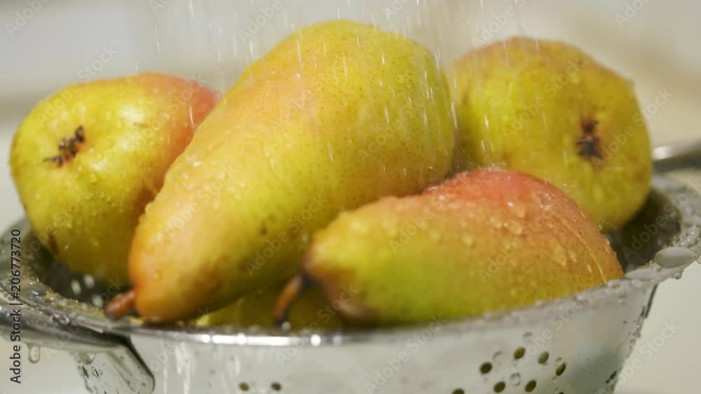 Washing ripe yellow red pears in colander closeup. Rinsing produce with water in slow motion. Washing ripe yellow red pears in colander closeup. Rinsing produce with water in slow motion.