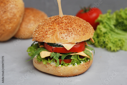 Fast food. Vegetarian Homemade Burger Cheese, Cucumber, Tomato and Lettuce, Salad. Tasty Sandwich for lunch Fresh Vegetables. Gray Textured background