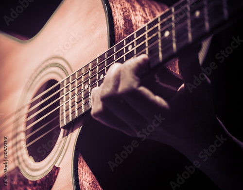 Man playing acoustic guitar on dark background. A musical concept.