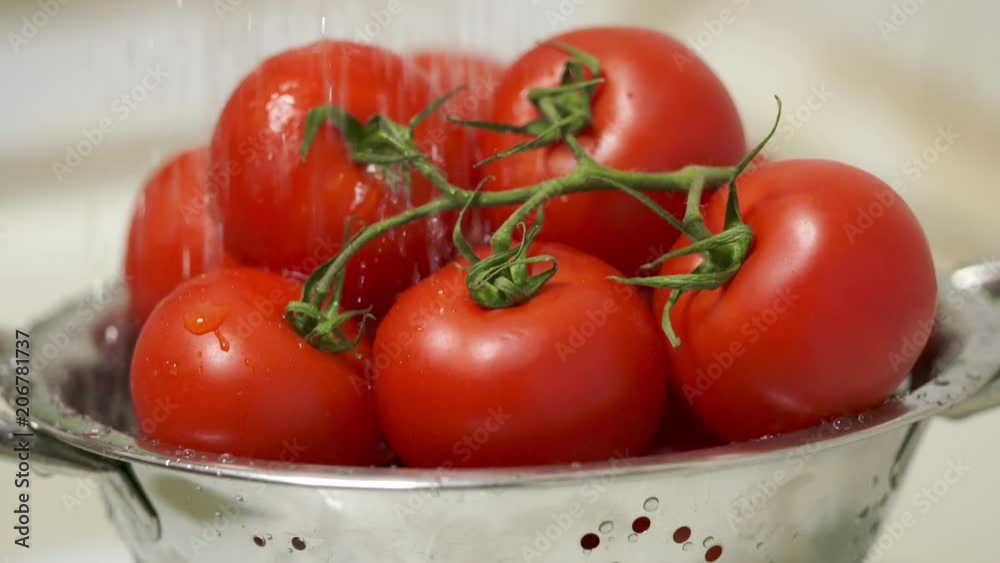 Washing fresh tomatoes in colander under running water in slow motion. Rinsing vegetables before cooking and eating. Washing fresh tomatoes in colander under running water in slow motion. Rinsing vegetables before cooking and eating.