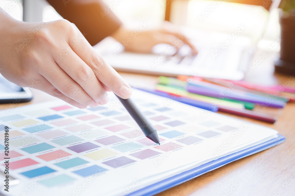 Creative designer hand using pen tablets pointing on color palette samples.Designer workplace. Creative designer hand using pen tablets pointing on color palette samples.Designer workplace.