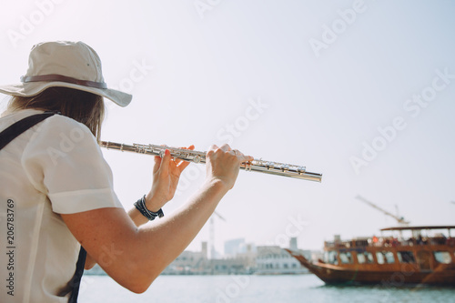 oung beautiful woman sitting at boat and playing the flute