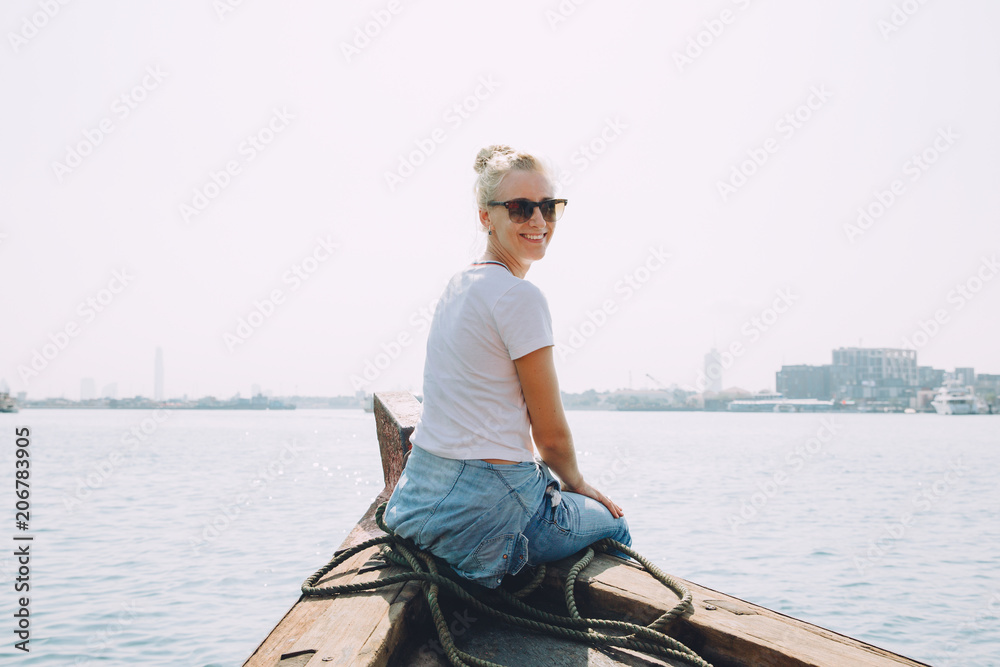 Young beautiful blonde woman sitting at pier and looking at sea