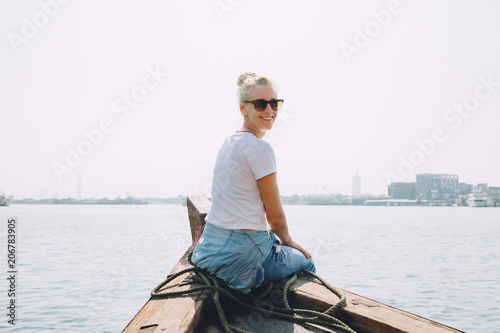 Young beautiful blonde woman sitting at pier and looking at sea