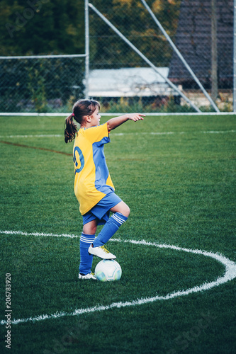 Young girl playing football at stadium with local girls football team and showing where to stand. Small city stadium located in Switzerland.