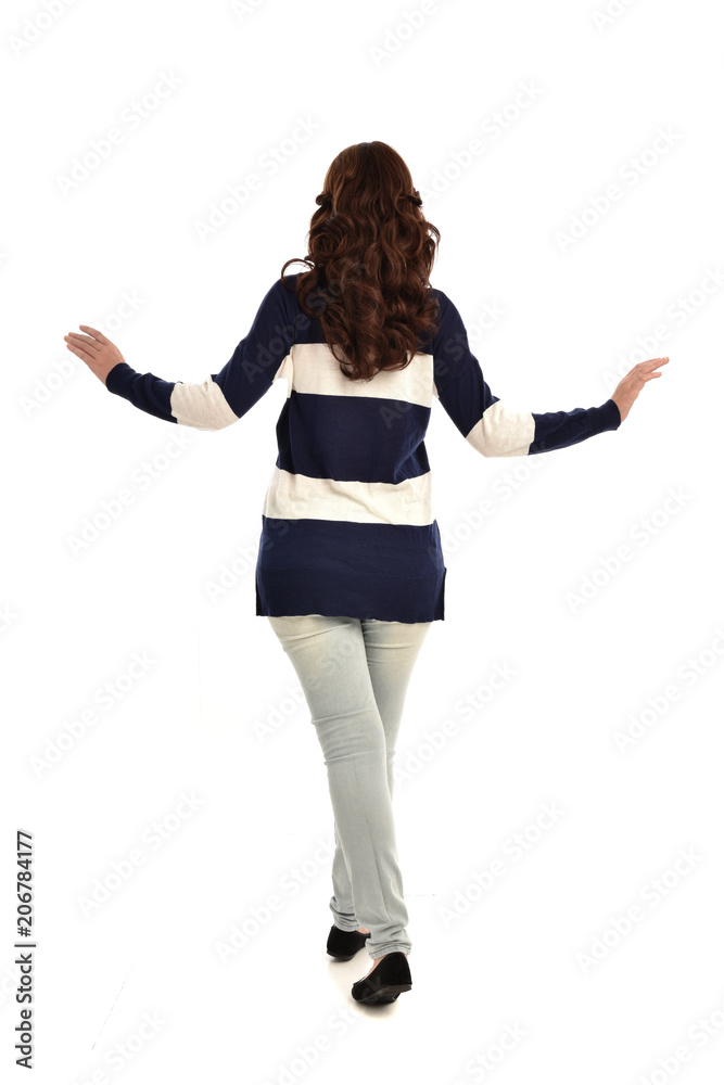 full length portrait of girl wearing striped blue and white jumper and jeans. standing pose facing away from the camera, on white studio background full length portrait of girl wearing striped blue and white jumper and jeans. standing pose facing away from the camera, on white studio background